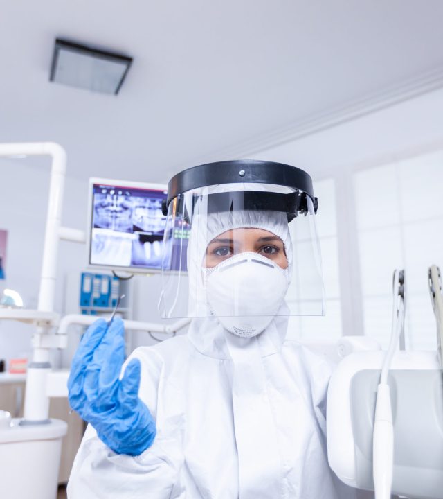 Pov of patient sitting on chair at dental office for teeth treatment Stomatolog wearing safety gear against coronavirus during heatlhcare check of patient.